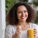 Joyful portrait of Maria Garcia, a NutriLife Indonesia client, holding a healthy smoothie and smiling.